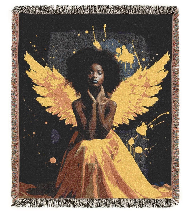 May include: A woven throw blanket featuring an artistic depiction of a person with large yellow wings, seated in a flowing yellow gown against a black background with yellow paint splatters. The blanket has a fringed edge.