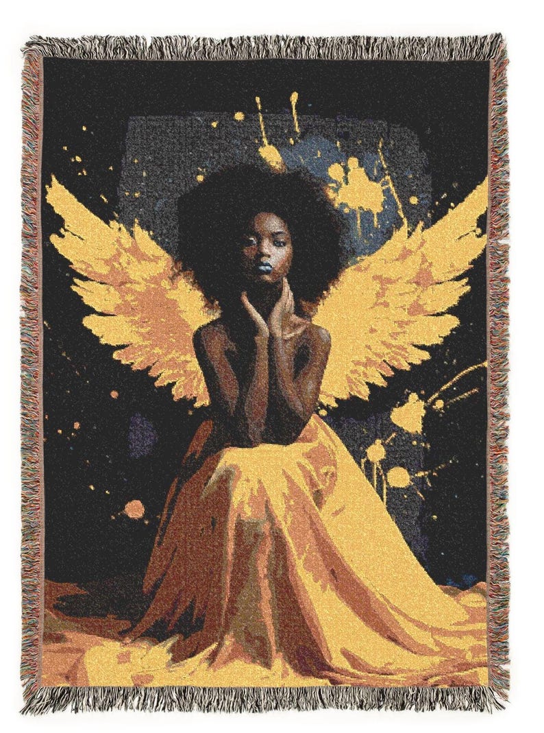 May include: Woven throw blanket featuring a woman with yellow angel wings and a yellow dress. The artwork has a black background with yellow paint splatters. The blanket has a fringed edge.