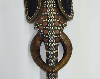 This African Babanki tribe elephant mask is hand-carved from wood and embellished with cowrie shells and coins. 30 x 12 x 6