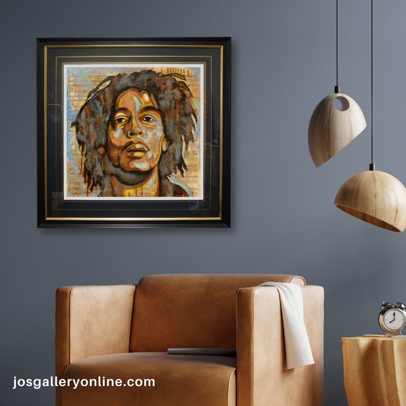 Pu&ograve; includere: Un dipinto incorniciato di un ritratto di Bob Marley con uno sfondo strutturato. Il dipinto &egrave; in una cornice nera con una cornice interna dorata. Il dipinto &egrave; appeso a una parete blu.
