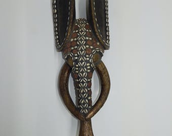 This African Babanki tribe elephant mask is hand-carved from wood and embellished with cowrie shells and coins. 34 x 12 x 6