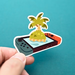 May include: A sticker of a Nintendo Switch console with a palm tree growing on a small island in the screen.