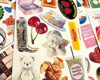 May include: A sheet of stickers featuring various designs, including a record player, a teddy bear, a cherub, a slice of toast, a cup of matcha, a cowboy hat, a boot, a cherry, a cake, and a bar of butter. The stickers are printed on white paper and have a glossy finish.