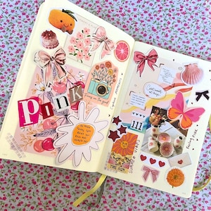 Pu&ograve; includere: Una pagina di scrapbook rosa e bianca con vari adesivi e ritagli. La pagina presenta una farfalla rosa, un sole con un viso sorridente, una macchina fotografica e le parole "Capture Moments" e "Summer Vibes".