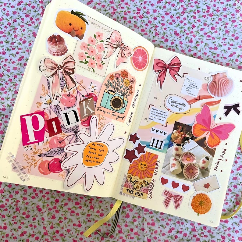 Pu&ograve; includere: Una pagina di scrapbook rosa e bianca con vari adesivi e ritagli. La pagina presenta una farfalla rosa, un sole con un viso sorridente, una macchina fotografica e le parole "Capture Moments" e "Summer Vibes".