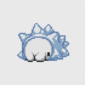 Puede incluir: Diseño de punto de cruz pixelado de una criatura blanca con detalles en azul claro. La criatura está tumbada, con una estructura espinosa y helada en la espalda. El diseño está sobre un fondo blanco.