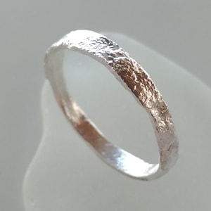 Puede incluir: Un anillo de plata con un acabado texturizado y martillado. El anillo es simple y elegante.