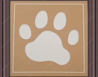 May include: A brown picture frame with a white paw print cutout in the center. The frame has a white mat around the paw print.