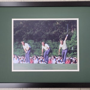 May include: A framed photograph of a golfer in mid-swing. The golfer is wearing a yellow shirt and plaid pants. The photo is set against a green background.