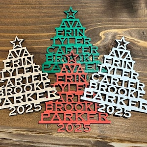 May include: Wooden Christmas tree ornaments in green, red, and white, each with a star on top and personalized names. The names Ava, Erin, Tyler, Carter, Brooke, and Parker are displayed, along with the year 2025.