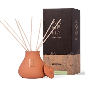 Könnte beinhalten: Terracotta-Diffuserflasche mit Holzstäbchen und Deckel. Die Flasche hat ein goldenes Etikett mit dem Text "KAHE NA COLLECTION" und "DIFUSOR AQUE CITRICO".