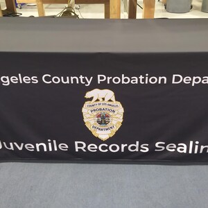 May include: Black table cover with white text that reads "Los Angeles County Probation Department" and "Juvenile Records Sealing". A gold badge with a bear and the words "County of Los Angeles Probation Department" is in the center of the table cover.