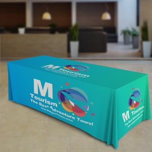 May include: A turquoise table cover with a white letter M and the text "Tourism The Best Adventure Tours!" and a colorful graphic of a plane and circles. The website address "nem.wotgmziuotm.www" is also included.