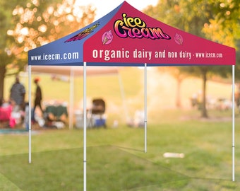 May include: A blue and red canopy tent with the words "Ice Cream" in a colorful font. The tent has the text "Organic dairy and non dairy - www.iceem.com" printed on it. The tent is set up on a grassy lawn.