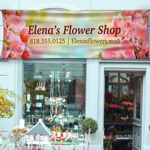 May include: A storefront with a banner that reads "Elena's Flower Shop" with a phone number and email address. The shop window displays floral arrangements and other decorative items.