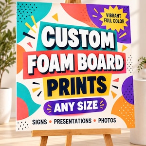 May include: A square foam board sign on a wooden easel featuring the text CUSTOM FOAM BOARD PRINTS ANY SIZE SIGNS PRESENTATIONS PHOTOS and VIBRANT FULL COLOR in a bold, multi-colored graphic design with teal, red, yellow, and purple shapes.