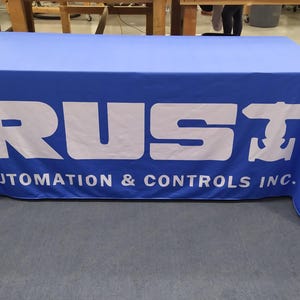 May include: A blue table cover with the white text "RUST AUTOMATION & CONTROLS INC." and a white anchor symbol.