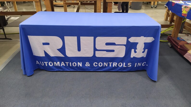 May include: A blue table cover with the white text "RUST AUTOMATION & CONTROLS INC." and a white anchor symbol.