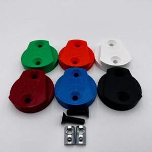 Könnte beinhalten: Eine Sammlung von sechs mehrfarbigen Fahrradplattenadaptern aus Kunststoff. Die Adapter sind grün, rot, weiß, weinrot, blau und schwarz. Auf jedem Adapter ist der Text "XSF SPD" aufgedruckt. Ebenfalls enthalten sind Schrauben und Metallplatten.
