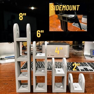 May include: Four gray plastic monitor stand risers in different heights: 2 inches, 4 inches, 6 inches, and 8 inches. The stands are designed for side mounting.
