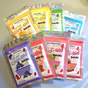 May include: Eight colourful packets of bath mix, each with a different flavour of Kool-Aid. The flavours are: Tangy Orange, Lemonade, Apple, Blue Raspberry, Wild Grape, Strawberry, Juicy Watermelon, and Cherry.