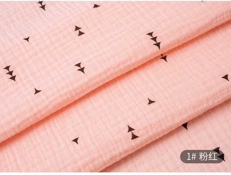 May include: Pink fabric with a repeating pattern of small black triangles. The fabric is folded in half and the text "1# 粉红" is visible in the bottom right corner.