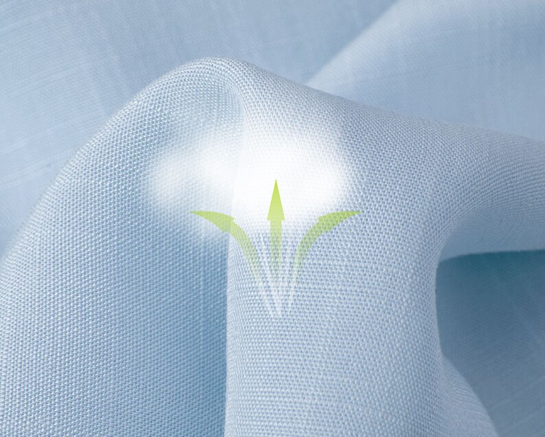 May include: Close-up of light blue fabric with a textured weave. The fabric is gently folded, creating soft shadows and highlights. A graphic of green arrows and a white glow suggest breathability.
