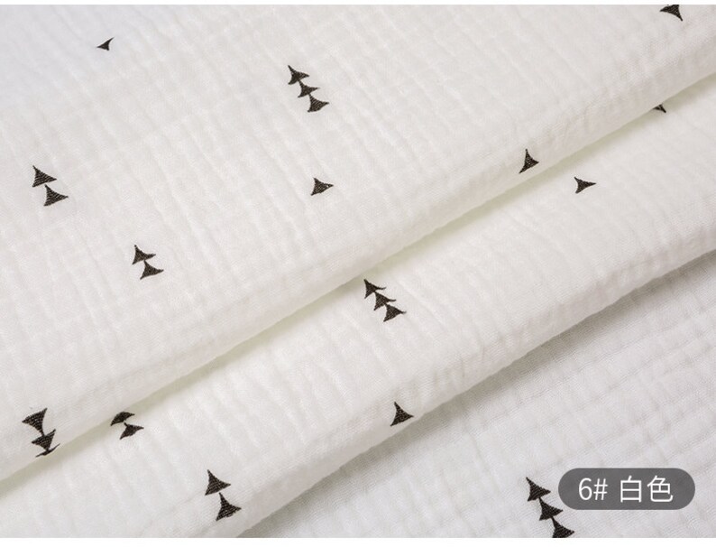 May include: White fabric with a subtle texture and a repeating pattern of small black triangles. The fabric is folded in half, and the text "6# 白色" is visible in the lower right corner.