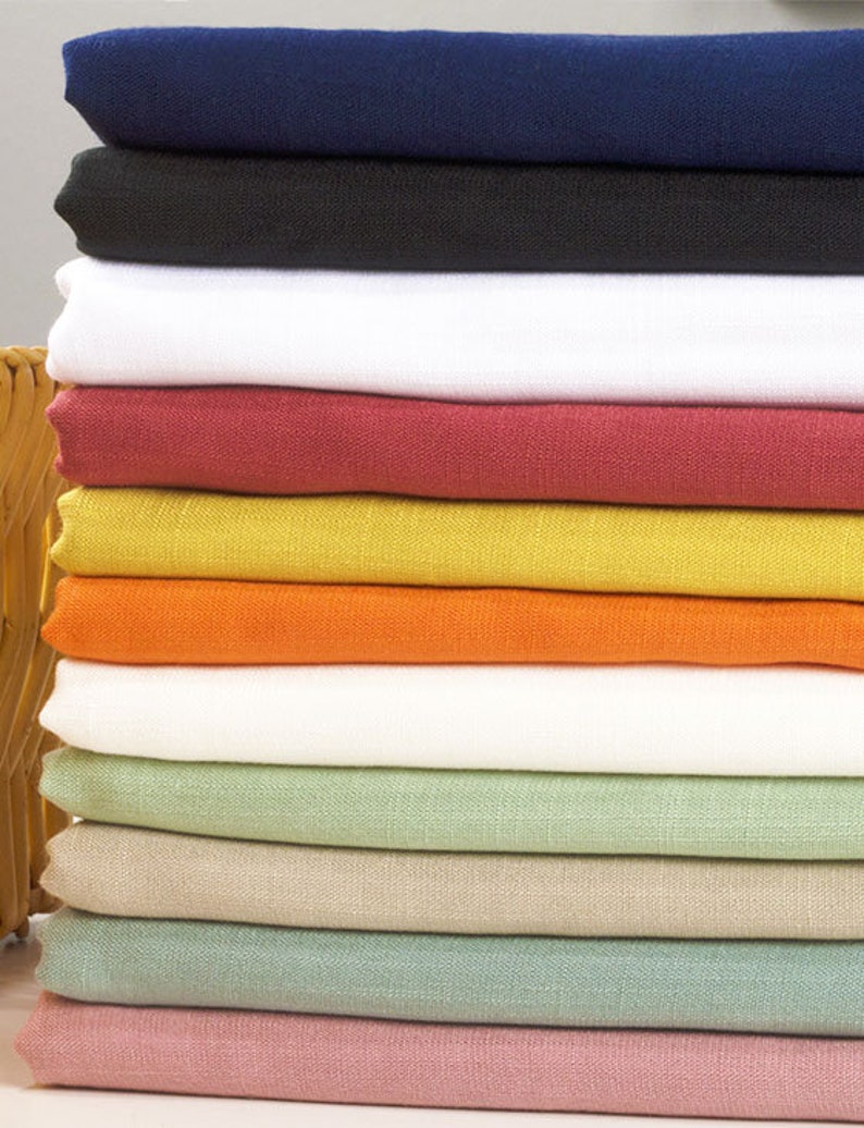 May include: A stack of fabric swatches in various colors, including navy blue, black, white, red, yellow, orange, light green, beige, teal, and pink.
