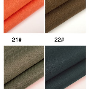 May include: Four fabric swatches in different colors: orange, brown, green, and dark blue. The swatches are folded in half and the fabric has a textured weave.