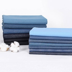 May include: A stack of blue denim fabric swatches, some are a lighter shade of blue and some are a darker shade of blue.