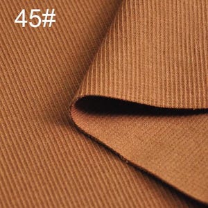 May include: Close-up of a brown ribbed fabric. The fabric is folded over itself, showing the texture of the material.