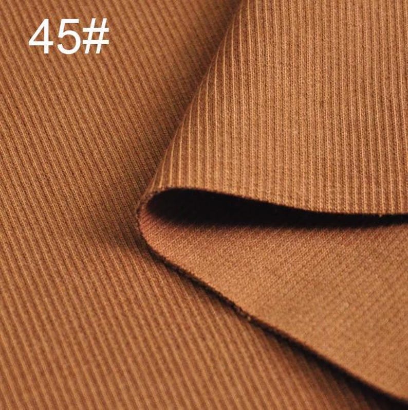 May include: Close-up of a brown ribbed fabric. The fabric is folded over itself, showing the texture of the material.