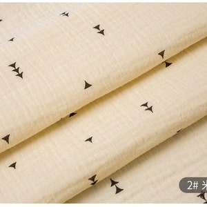 May include: Close-up of a beige fabric with a repeating pattern of black arrows. The fabric is folded in thirds, and the text "2# 米色" is visible in the bottom right corner.