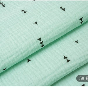 May include: A close-up of a light green fabric with a repeating pattern of black arrows. The fabric is folded in half, and the text "5# 箭头" is visible in the lower right corner.