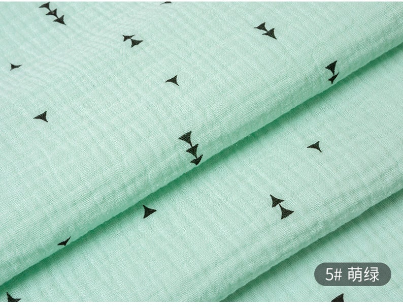 May include: A close-up of a light green fabric with a repeating pattern of black arrows. The fabric is folded in half, and the text "5# 箭头" is visible in the lower right corner.