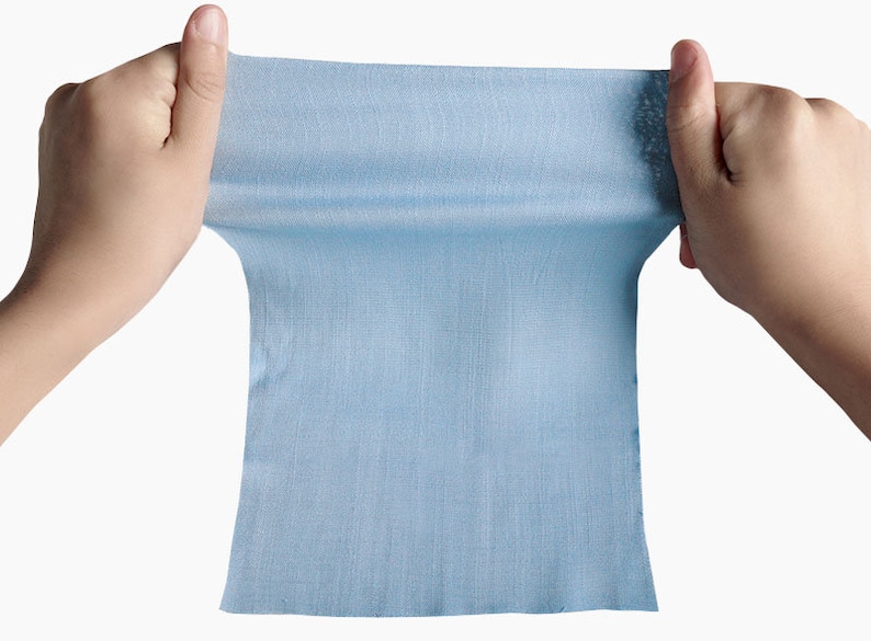 May include: A light blue fabric swatch being stretched out by two hands.