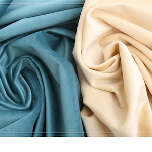 May include: Close-up of two fabric swatches. One is a light blue velvet fabric and the other is a cream colored velvet fabric.
