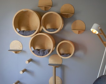 Puede incluir: Un árbol para gatos de pared con múltiples estantes circulares y un poste para rascar. Los estantes son de madera y tienen un acabado natural. El poste para rascar está cubierto de cuerda de sisal. El árbol para gatos es una excelente manera de proporcionarle a tu gato un lugar para trepar, jugar y relajarse.