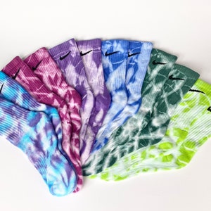 Könnte beinhalten: Ein Set mit acht bunten Batik-Socken mit einem schwarzen Nike-Swoosh-Logo auf jeder Socke.