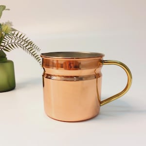 May include: A copper mug with a brass handle. The mug has a hammered finish and is perfect for serving cocktails or other beverages.