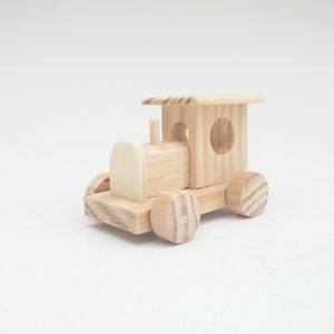 May include: A wooden toy train with a brown wooden caboose and four wheels. The train is made of natural wood and has a simple design.