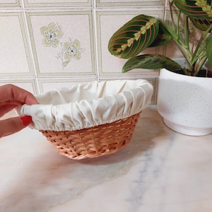 Op de afbeelding: Een rieten broodmand met een witte voering.