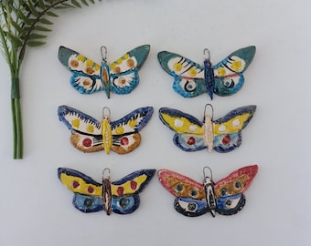 May include: Six colorful ceramic butterfly ornaments with intricate details. Each butterfly has a different color scheme and pattern, including blue, yellow, red, and green.