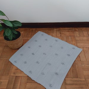 Puede incluir: Una alfombra de ba&ntilde;o gris claro con una superficie texturizada y un patr&oacute;n repetitivo de peque&ntilde;as flores en relieve.