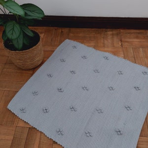 Puede incluir: Una alfombra gris claro con una superficie texturizada y un patr&oacute;n repetitivo de peque&ntilde;os c&iacute;rculos en relieve.
