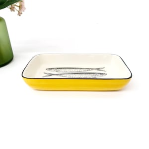 Pode incluir: Uma travessa retangular de cer&acirc;mica com exterior amarelo brilhante e interior branco. Duas ilustra&ccedil;&otilde;es detalhadas de peixes em preto e branco est&atilde;o centradas dentro da travessa. A borda &eacute; delineada com uma fina borda preta.
