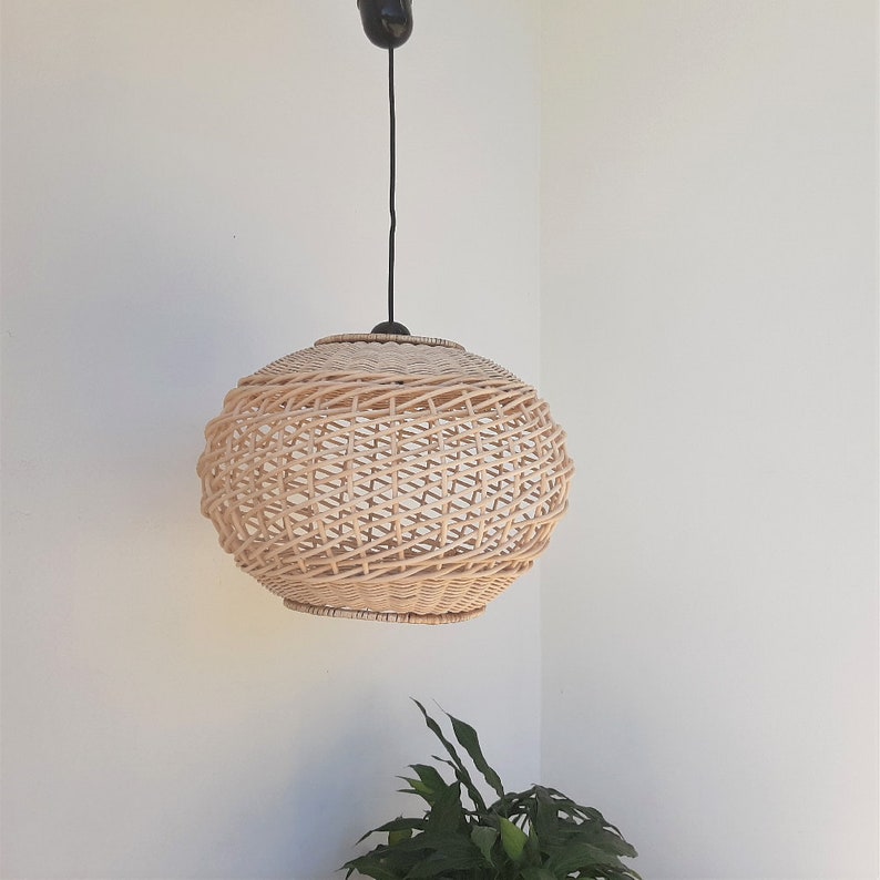 May include: A round, natural woven wicker pendant light fixture with a black cord hanging from the ceiling.