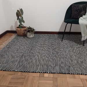 May include: A black and white patterned rug with a fringe border. The rug is made of a woven material and has a textured surface.