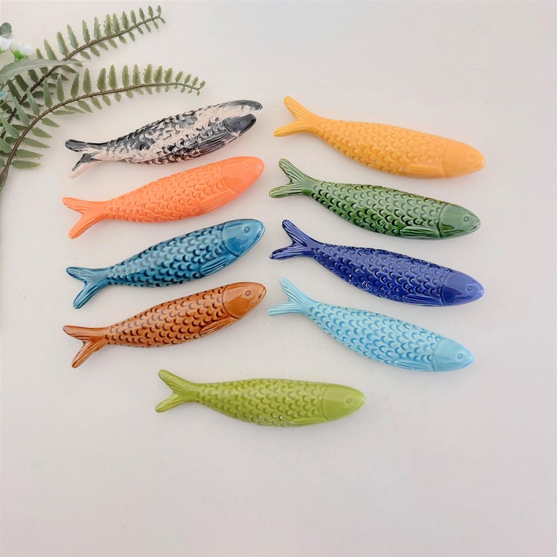Puede incluir: Diez figuritas de pescado de cer&aacute;mica en varios colores, incluyendo naranja, azul, verde y amarillo. Cada pez tiene una superficie detallada y texturizada.